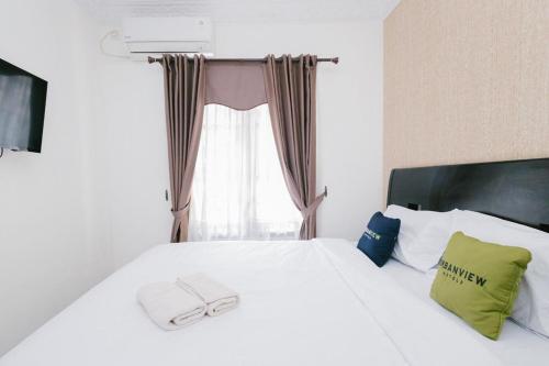 a bedroom with a white bed with a window at Urbanview Hotel Sultan Palace Malang by RedDoorz in Dau