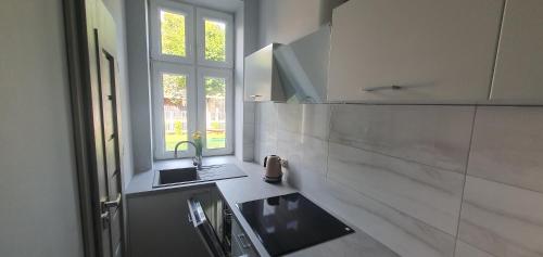 a white kitchen with a sink and a window at Apartament Starówka in Konin