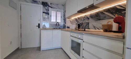 a kitchen with white cabinets and a counter top at Principado Benidorm Suites Levante in Benidorm