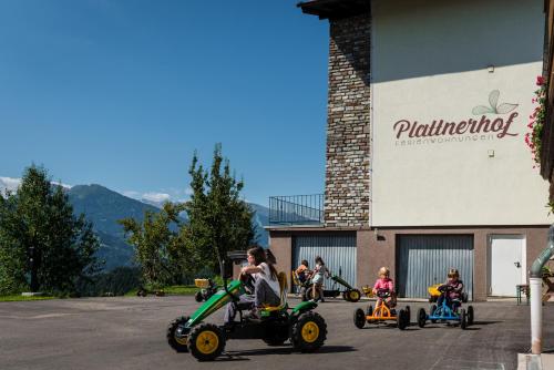 a group of children riding on toy cars in a parking lot at Ferienwohnungen Plattnerhof in Terfens