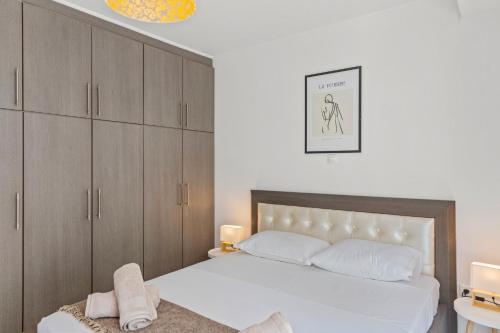a bedroom with a white bed and wooden cabinets at Rhodian Filoxenia in Rhodes Town