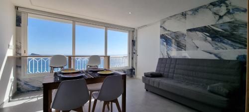 a dining room with a table and chairs and a couch at Principado Benidorm Suites Levante in Benidorm