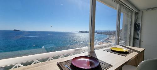 a room with a table with a view of the ocean at Principado Benidorm Suites Levante in Benidorm
