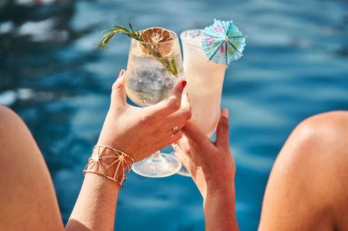 a woman holding up a drink by the pool at Fairmont Bab Al Bahr in Abu Dhabi