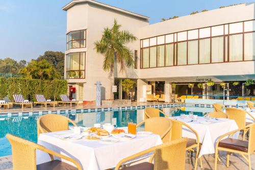 un restaurant avec des tables et des chaises à côté d'une piscine dans l'établissement Best Western Resort Country Club, à Gurgaon