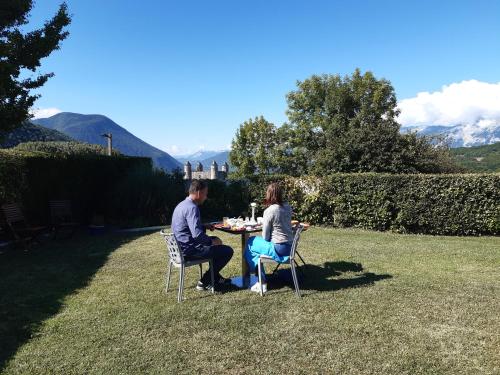 a man and woman sitting at a table in the grass at Un petit coin de paradis à Haute Jarrie in Jarrie