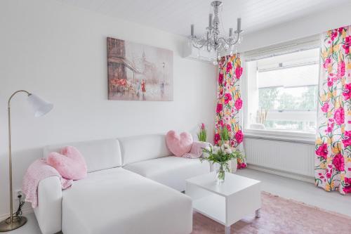 a white living room with a white couch and a chandelier at City Holiday Apartments 2 in Rovaniemi
