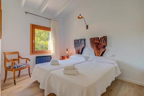 Un dormitorio blanco con 2 camas y una silla en Villa Can Gallardo, en Pollensa