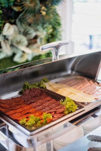a counter with a tray of meats and vegetables at RIVA Szeged in Szeged