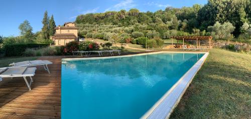 a large swimming pool with a house in the background at Fattoria Le Fonti in Poggibonsi