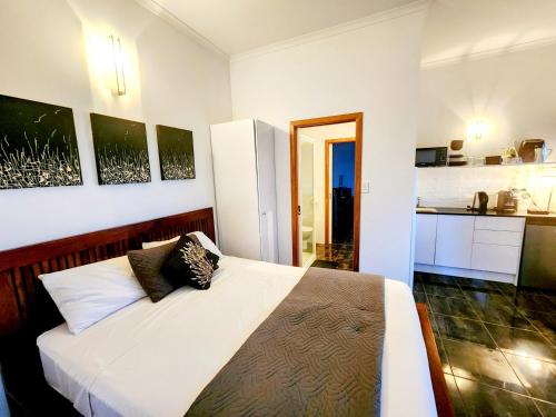 a bedroom with a white bed and a kitchen at Bella Vista on Nara Stay 4n each guest get free Day trip Kens Klassic Kombi in Airlie Beach