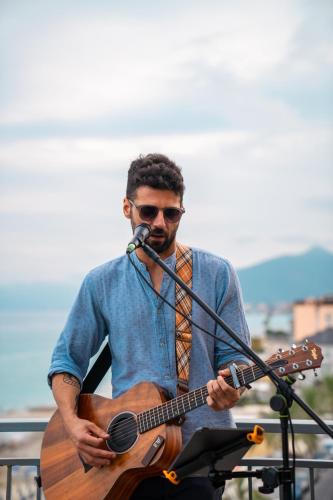 a man playing a guitar and a microphone at Hotel Jolly Roger in Pietra Ligure