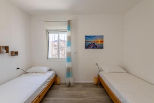 two beds in a room with white walls and a window at Desert and Sea-penthouse Full Sea view in Eilat