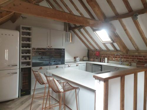 a kitchen with white cabinets and a counter with stools at Luxury barn with hot tub (Dogs Welcome) in Roughton