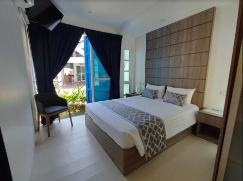 a bedroom with a large bed and a chair at Solesor Kampong Beach Resort in Port Dickson