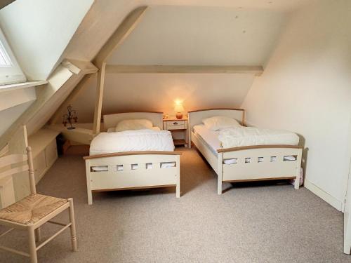 a attic room with two beds and a chair at Maison Jullouville, 6 pièces, 11 personnes - FR-1-361-466 in Jullouville-les-Pins