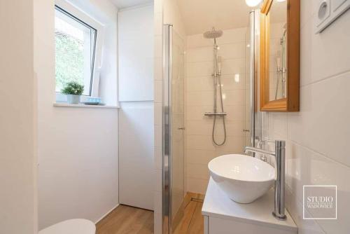 biała łazienka z umywalką i prysznicem w obiekcie N-apartament Wadowice w Wadowicach