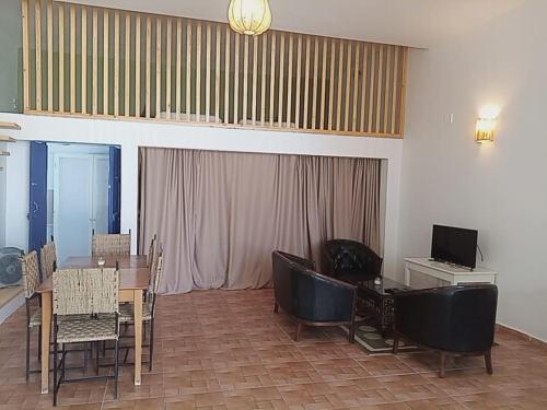 a dining room with a table and chairs and a television at Auberge du Marabout in Sidi Kaouki