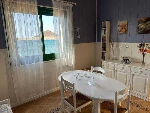 einen weißen Tisch und Stühle in einem Zimmer mit Fenster in der Unterkunft Casa El Picacho in El Médano