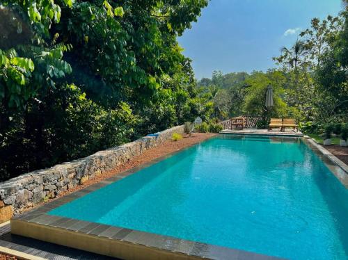 a large blue swimming pool with a stone wall at The Jungle Loft Galle in Galle