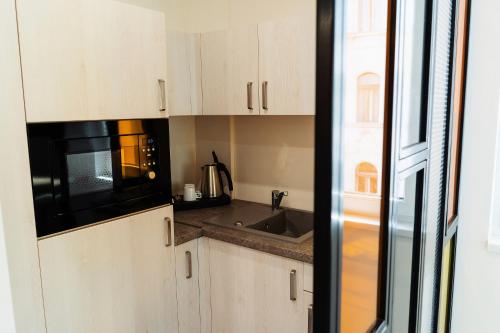a kitchen with white cabinets and a black microwave at RIVA Szeged in Szeged