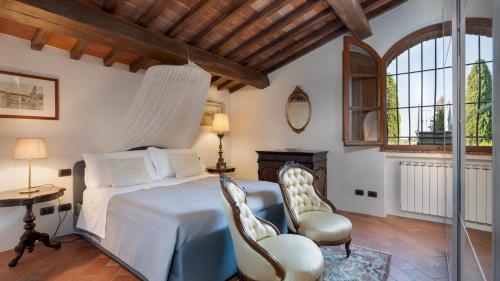 een slaapkamer met een bed en een tafel en stoelen bij VILLA I LEVRIERI 8, Emma Villas in Tavarnelle in Val di Pesa