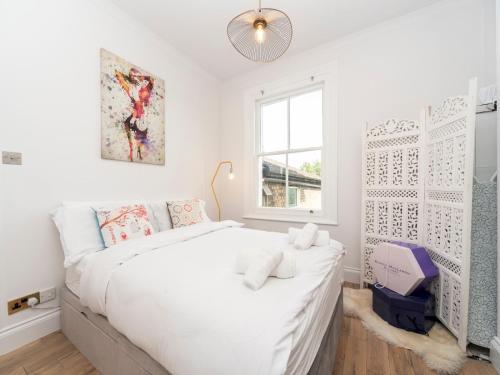 a white bedroom with a large bed and a window at Pass the Keys Cosy and Chic Flat Near Greenwich Park in London