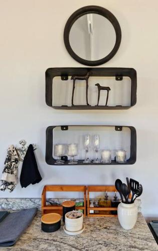 a mirror on a wall with a table with dishes at Klawerjas Flute Cottage in Robertson