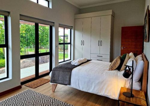 a bedroom with a large bed and some windows at Klawerjas Flute Cottage in Robertson