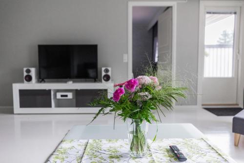 un jarrón de flores sobre una mesa en la sala de estar en Arctic Holiday Apartments 3, en Rovaniemi