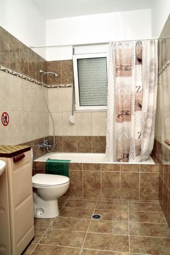 a bathroom with a toilet and a tub and a window at ANTONIOS apartments in Archangelos