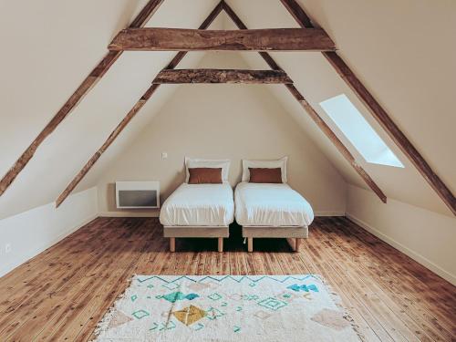 a attic room with two beds and a rug at Domaine du Mimosa in Perros-Guirec