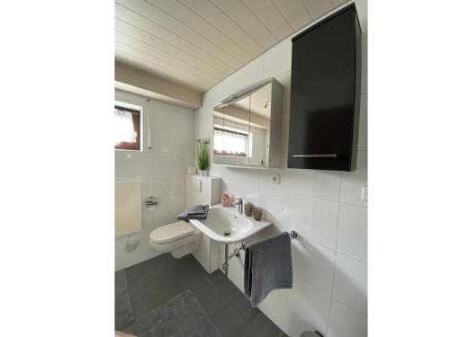 a white bathroom with a sink and a mirror at Ferienwohnung am Südhang in Gernsbach