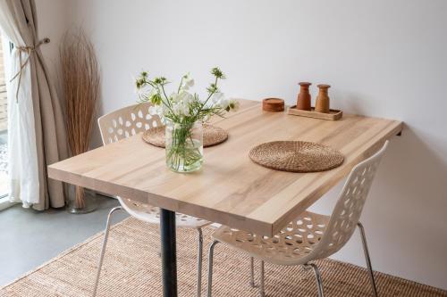 una mesa de madera con sillas y un jarrón de flores en Malevik Tiny House, en Kullavik