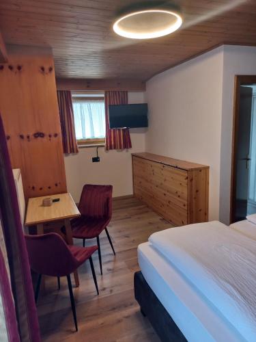 a bedroom with a bed and a desk and a table at Garnì Piz da L'Ander in Corvara in Badia