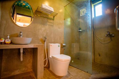 y baño con aseo, lavabo y ducha. en Sườn Đồi Bungalow Homestay, en Phong Nha