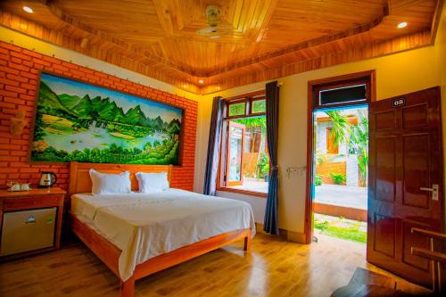 1 dormitorio con 1 cama y una pintura en la pared en Sườn Đồi Bungalow Homestay, en Phong Nha