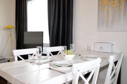 a white table with white chairs and plates and wine glasses at Nordica central apartment in Rovaniemi