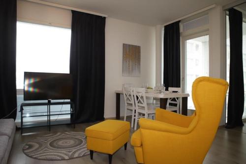 a living room with a yellow chair and a table at Nordica central apartment in Rovaniemi
