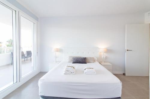 um quarto branco com uma cama grande e uma janela em Global Properties, Apartamento con 2 terrazas en Gran Canet em Canet d'En Berenguer