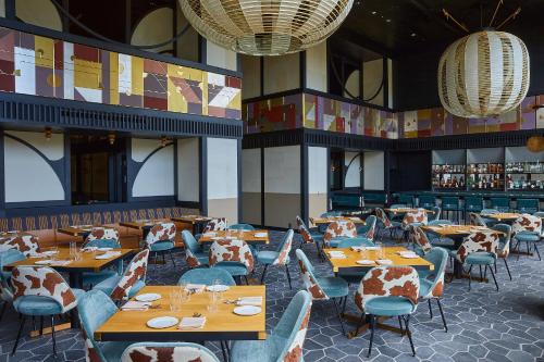 京都市にあるエースホテル京都の木製のテーブルと椅子、照明が備わるレストラン