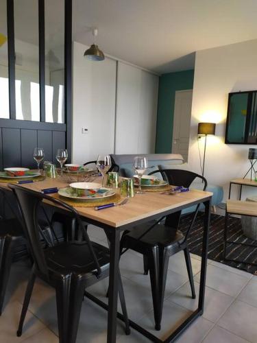 - une table en bois avec des chaises et des verres à vin dans l'établissement Très bel F2 avec vue mer, à Langrune-sur-Mer