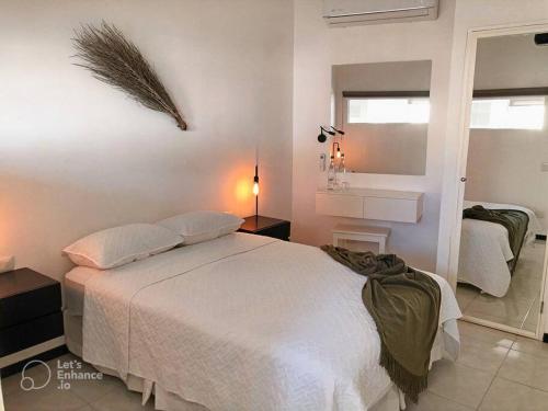 a bedroom with a white bed and a mirror at Increíble departamento en malecón frente al mar in Mazatlán