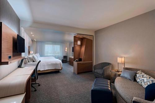 シュガーランドにあるCourtyard by Marriott Houston Sugar Land/Lake Pointeのベッドとソファ付きのホテルルーム