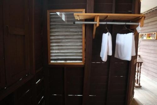 a closet with two white shirts hanging on a rack at บ้านน่านโฮมสเตย์ in Nan