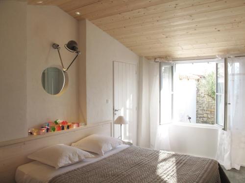 a bedroom with a bed and a large window at Hôtel Le Sénéchal in Ars-en-Ré