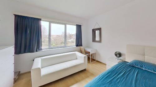 a bedroom with a white couch and a bed at nice and cosy apartment in Edegem