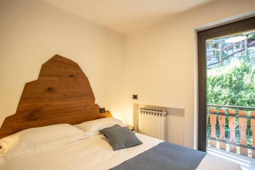 een slaapkamer met een bed met een houten hoofdeinde en een raam bij La Rosa delle Alpi Luxury Apartment in Chamois