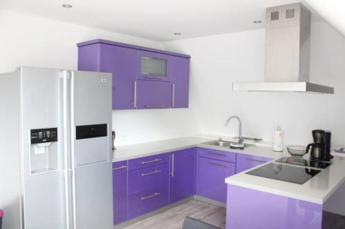 a kitchen with purple cabinets and a white refrigerator at Holländer Flair Friedrichstadt in Friedrichstadt