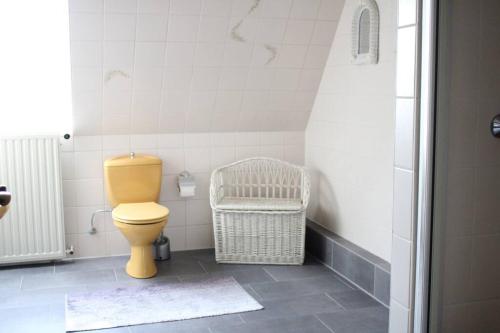 a bathroom with a yellow toilet and a basket at Holländer Flair Friedrichstadt in Friedrichstadt